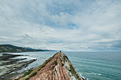 Distant View Of Person Standing On Top Of Rock In Zumaia, Basque Country, Spain
