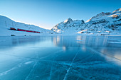 The Bernina Express train runs beside the frozen Lago Bianco, Bernina Pass, canton of Graubunden, Engadine, Switzerland, Europe