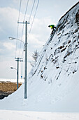 Snowboarder rides down on chainlink fence in Otaru, Japan