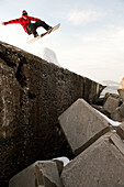 Low angle view of snowboarder jumping on rock