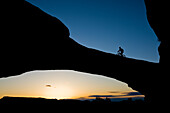 Jess Reilly mountain biking across an arch near Moab, Utah.
