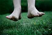 Bare feet hover above green grass, Maine.