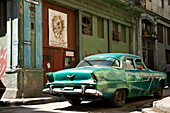 Havana, Cuba - an old car moves down O'Relly through the side streets of Old Havana past an arts organization tucked in an old building