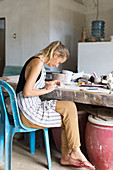 Artistic Woman Using Brush On Mold In Ceramic Workshop