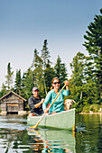 Smiling Man And Woman Canoeing With Their Dog On Caspian Lake