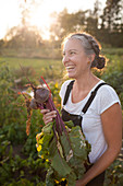 Glückliche Frau mit einem Büschel frisch gepflückter Rüben aus ihrem Garten in Fort Langley