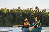 A Young Couple Paddles A Canoe On Long Pond In Maine's North Woods Near Greenville, Maine