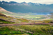 Distant View Of A Woman Rides Along A Mountain Road In North Iceland