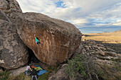 Male Climber Bouldering On Rock In Desert Landscape