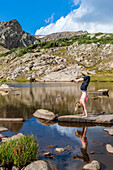 An Young Woman Practices Yoga On A Lake In The Colorado Wilderness