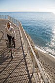 Elevated perspective of woman riding bike by sea