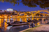 Man watching Porto and wine boats on Douro River,  Oporto city, Porto district, Portugal, Europe