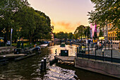 The Netherlands, Europe, sailing boat in Amsterdam canal at sunset