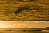 Sonnenuntergang mit orange Licht über dem Ozean, die von einer Schicht von niedrigen Wolken, Flatey Insel, Island überragt wird