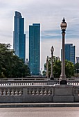 The bridge over the rail station of Chicago with light poles and the two big skyscraper in background