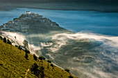 The town of Castelluccio di Norcia in the fog at sunset, Monti Sibillni NP, Umbria, Italy