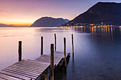 Ein Pier in Sulzano, vor Montisola und Peschiera Maraglio Stadt während eines Wintersonnenuntergang, Provinz Brescia, Iseosee, Lombardei, Italien