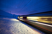 Bernina Express Zug fährt schnell in der verschneiten Landschaft in der Dämmerung Bernina Pass Kanton Graubünden Engadin Schweiz Europa