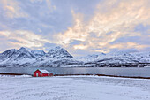 Typische Rorbu in der verschneiten Landschaft umgeben von den gefrorenen Meer und hohen Gipfeln Svensby Lyngen Alpen Tromsø Norwegen Europa