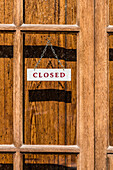 'Ein ''Geschlossen-Schild'' an einem Laden mit Holztür in der Nebensaison, Port de Sóller, Mallorca, Spanien '