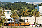 View from the harbour at the promenade with the old tram and the Tramuntana Mountains in the background, Port de Sóller, Mallorca, Spain