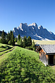 Small wooden cabin in front of the Geisler peaks, Dolomites, South Tirol, Italy