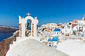Ein Kirchendach und Glocke mit den weißen gewaschenen Steinmauern und blauen Kirchenkugeln von Oia, Santorini, Kykladen, griechischen Inseln, Griechenland, Europa