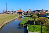 Weißer Schwan im Kanal umgeben von Wiesen und typischen Holzhäusern, Marken, Wasserland, Nordholland, Niederlande, Europa