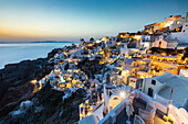 Sonnenuntergang über den weißen Steingebäuden und Windmühlen von Oia auf der Spitze von Santorinis Caldera, Santorini, Kykladen, griechische Inseln, Griechenland, Europa
