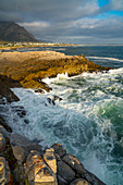 Seelandschaft über stürmisches Meer und Felsen bei der Einstellung der Sonne bei Sievers Point, Hermanus, Südafrika, Afrika