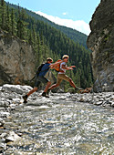 Father and son jumping across mountain river