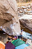 Eine junge Passform weiblich klettert auf einem umgedrehten Felsblock in Colorado