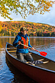 A Man Canoeing On Greenough Pond In Fall At Wentworths Location, New Hampshire