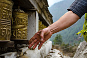Man spins a Tibetan Buddhist prayer wheel along trail to Mount Everest in Sagarmatha National Park