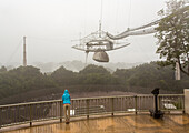A woman stands next to the world's largest satellite dish at Arecibo Observatory in Puerto Rico.