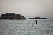 A young woman paddles a SUP in Pacific Rim National Park, Vancouver Island, British Columbia