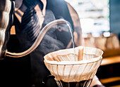 Ein Barista gießt heißes Wasser über handwerkliche Kaffeebohnen in einem Café in San José, Costa Rica