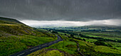 'Regen fällt von einem stürmischen Himmel über eine üppige, grüne Landschaft; North Yorkshire, England'