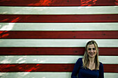 Porträt der lächelnden Mid-Adult Frau gegen Wand mit roten und weißen Streifen