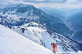 Woman backcountry skiing ascending towards Grosses Mosermandl, Tauern highway in background, Grosses Mosermandl, Radstadt Tauern, Carinthia, Austria