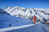 Woman backcountry skiing ascending towards Reichenspitze, Rauchkofel in background, Reichenspitze, Zillertal Alps, Tyrol, Austria