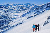 Three persons backcountry skiing ascending towards Grundschartner, Hochgall in background, Grundschartner, Zillertal Alps, Tyrol, Austria