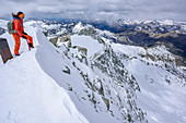 Frau auf Skitour blickt vom Gipfel in die Nordwand der Cima Presanella, Presanella, Adamellogruppe, Trentino, Italien