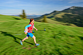 Woman trail running crossing meadow, Farrenpoint, Bavarian Alps, Upper Bavaria, Bavaria, Germany