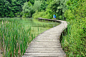 Two persons walking on pier through National Park Plitvice Lakes, Plitvice Lakes, National Park Plitvice Lakes, Plitvice, UNESCO world heritage site National Park Lake Plitvice, Croatia