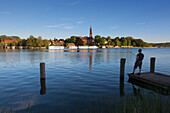 Person fishing, view over the lake to Malchow monastery, Mueritz-Elde-Wasserstrasse, Mecklenburgische Seenplatte, Mecklenburg-West Pomerania, Germany