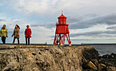 'Tourists walking on a pier and Herd Groyne Lighthouse; South Shields, Tyne and Wear, England'
