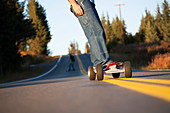 Young men skateboarding down a road, Homer, Alaska, United States of America