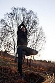 A woman does yoga on a hillside in autumn, Alaska, United States of America