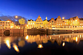 Dusk lights on typical houses and bridge reflected in a canal of the River Spaarne, Haarlem, North Holland, The Netherlands, Europe
